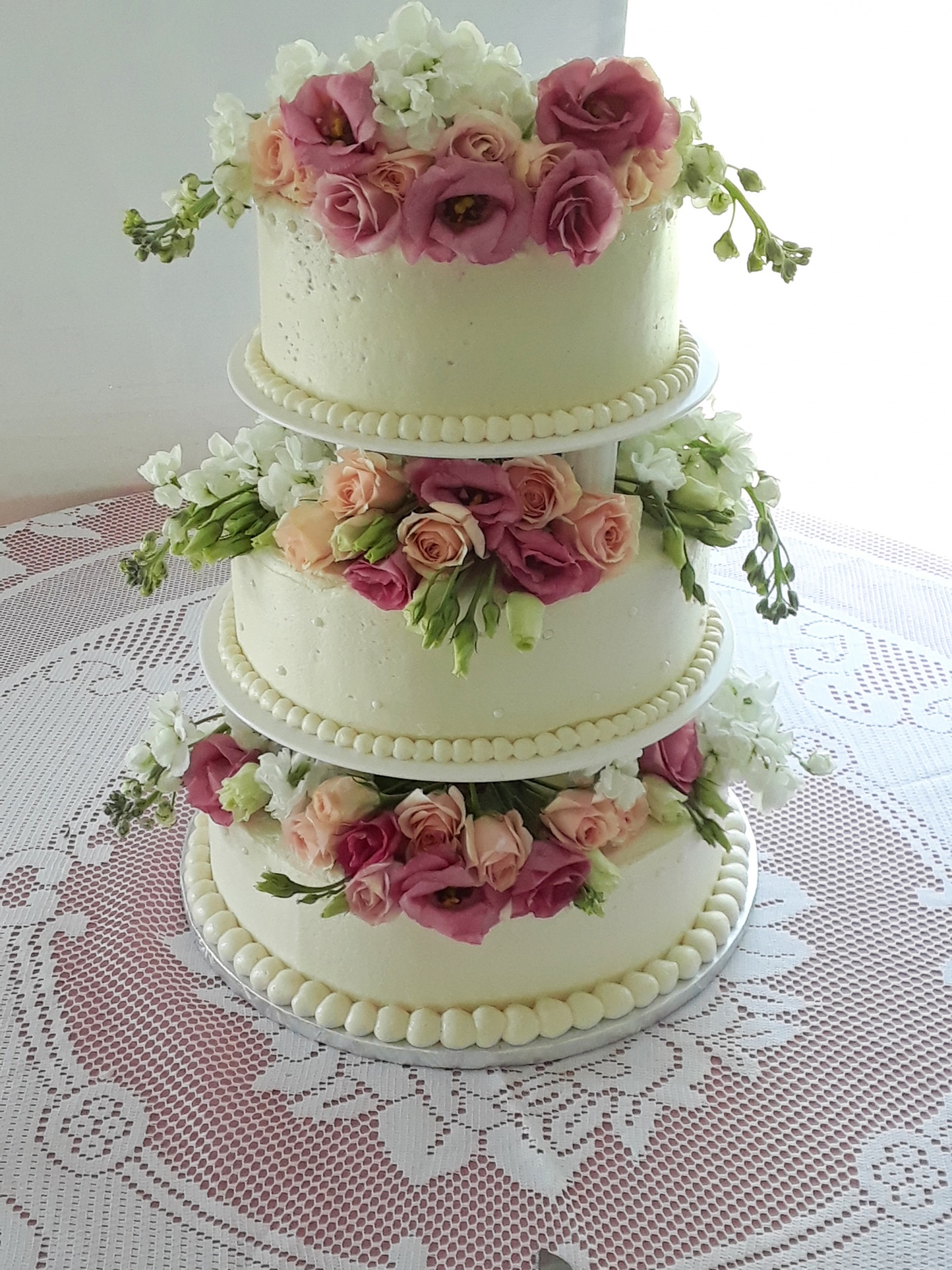 Wedding cake with white frosting, tiers, and fresh flowers
