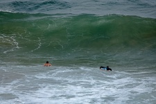 Surfers Rowing Towards Large Wave