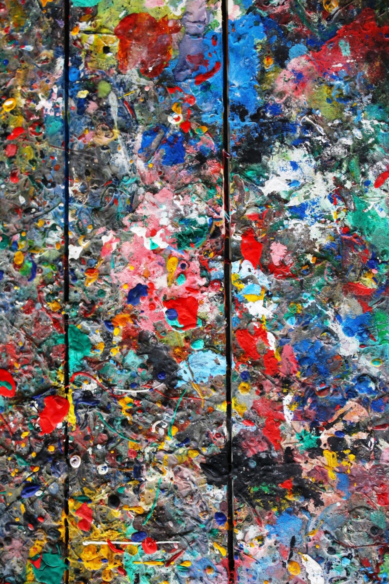 Messy colorful wooden board covered in paint splats used as an artists palette