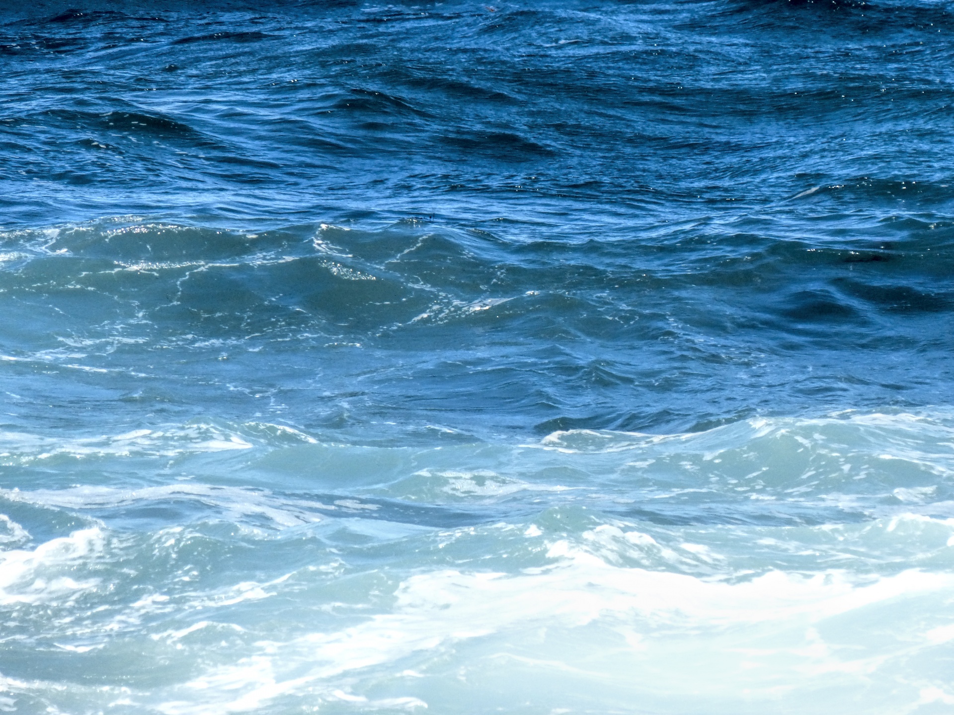 Ocean waves in multiple color shades of blue. from deep turquoise to pale blue-green