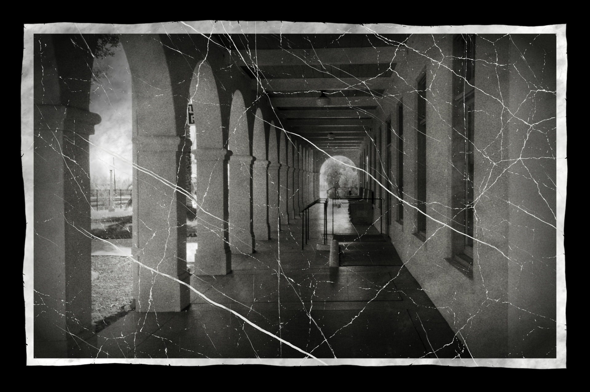 cracked black and white photo of adobe hallway with arches