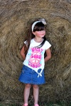 Little Girl In Front Of Hay Bale