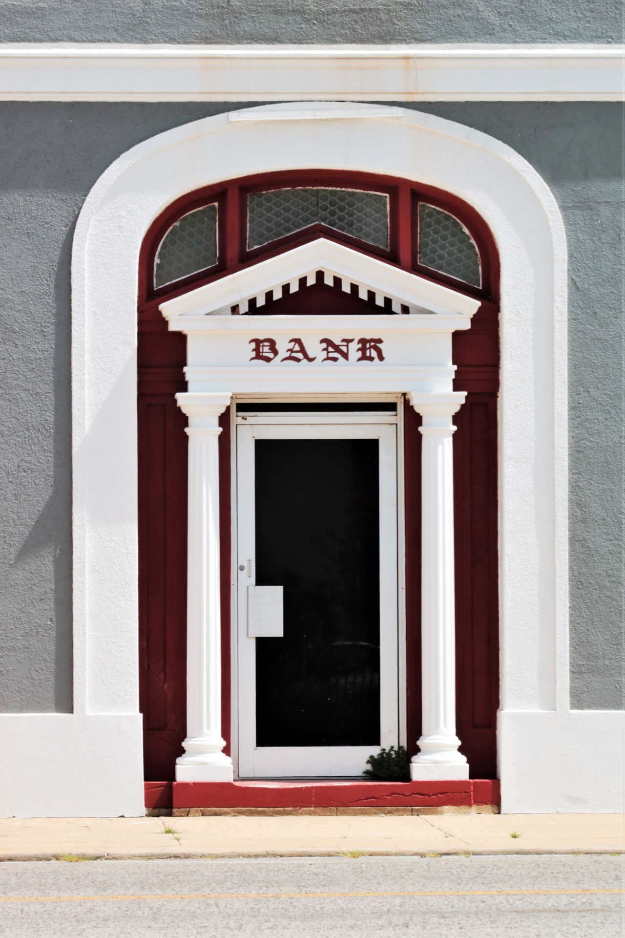 The door of a small town bank, with white arched doorway and columns.