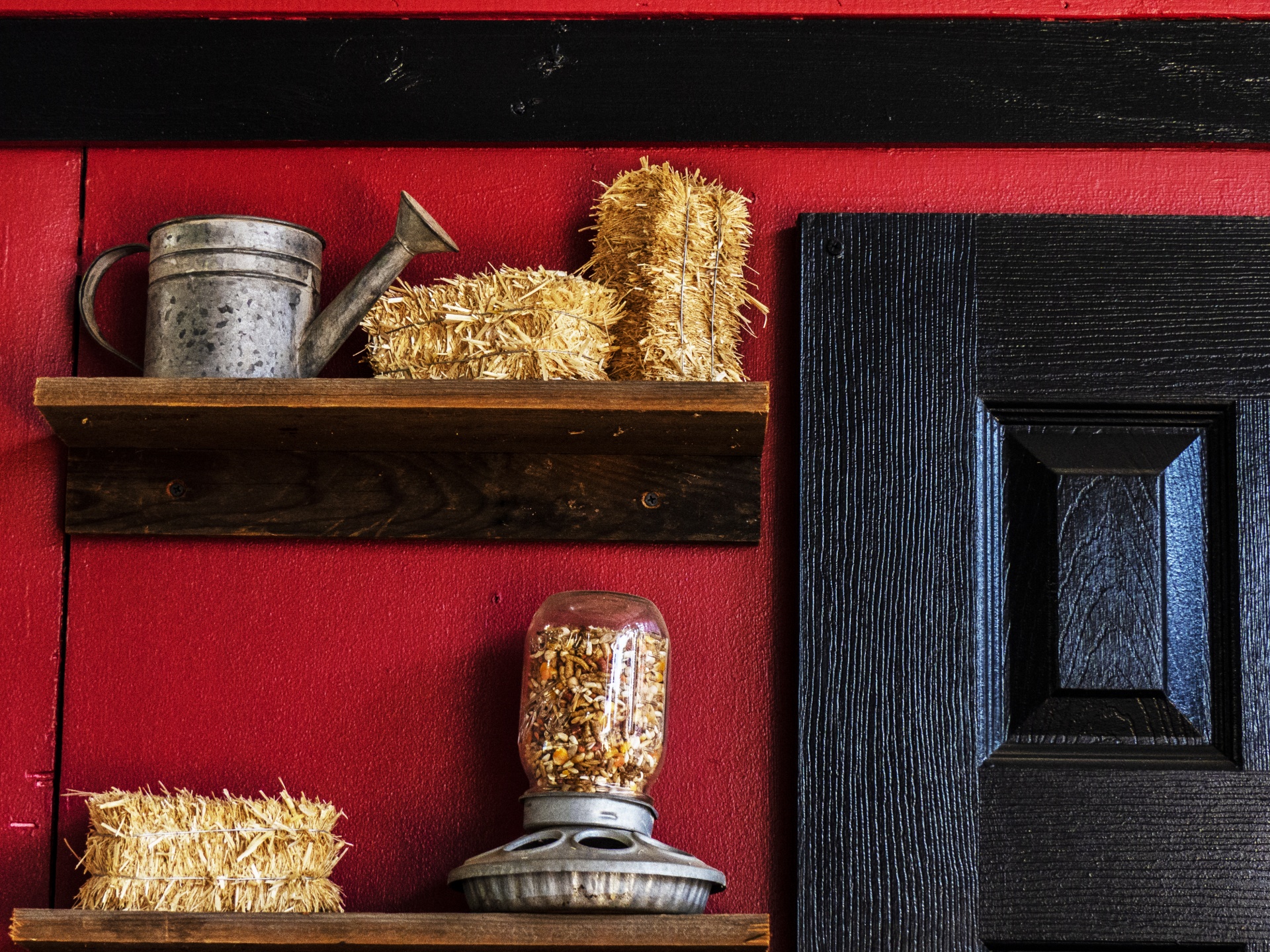 Red wall and a black door with an old jar on a shelf