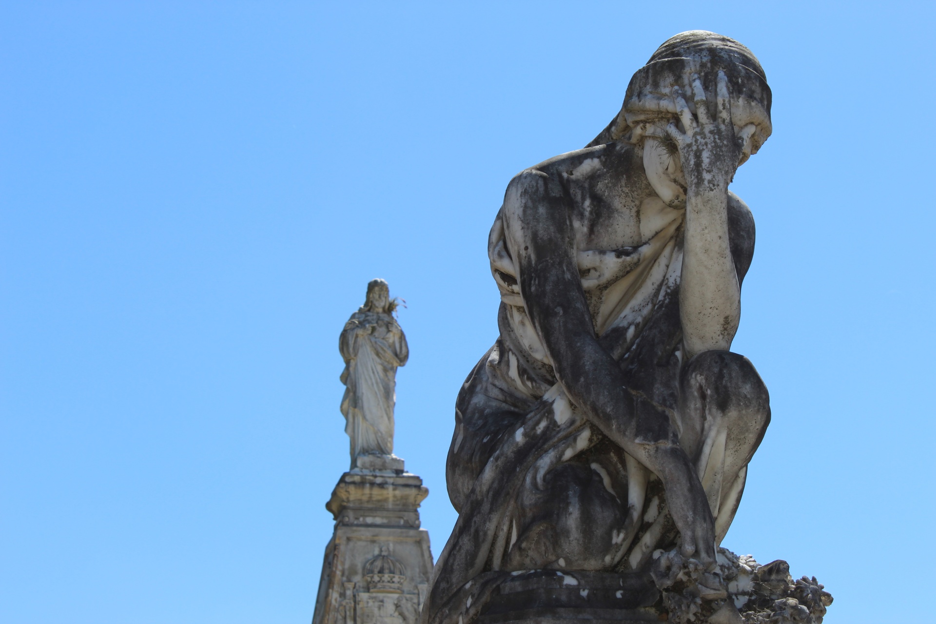 Sad cemetery marble sculpture under blue sky