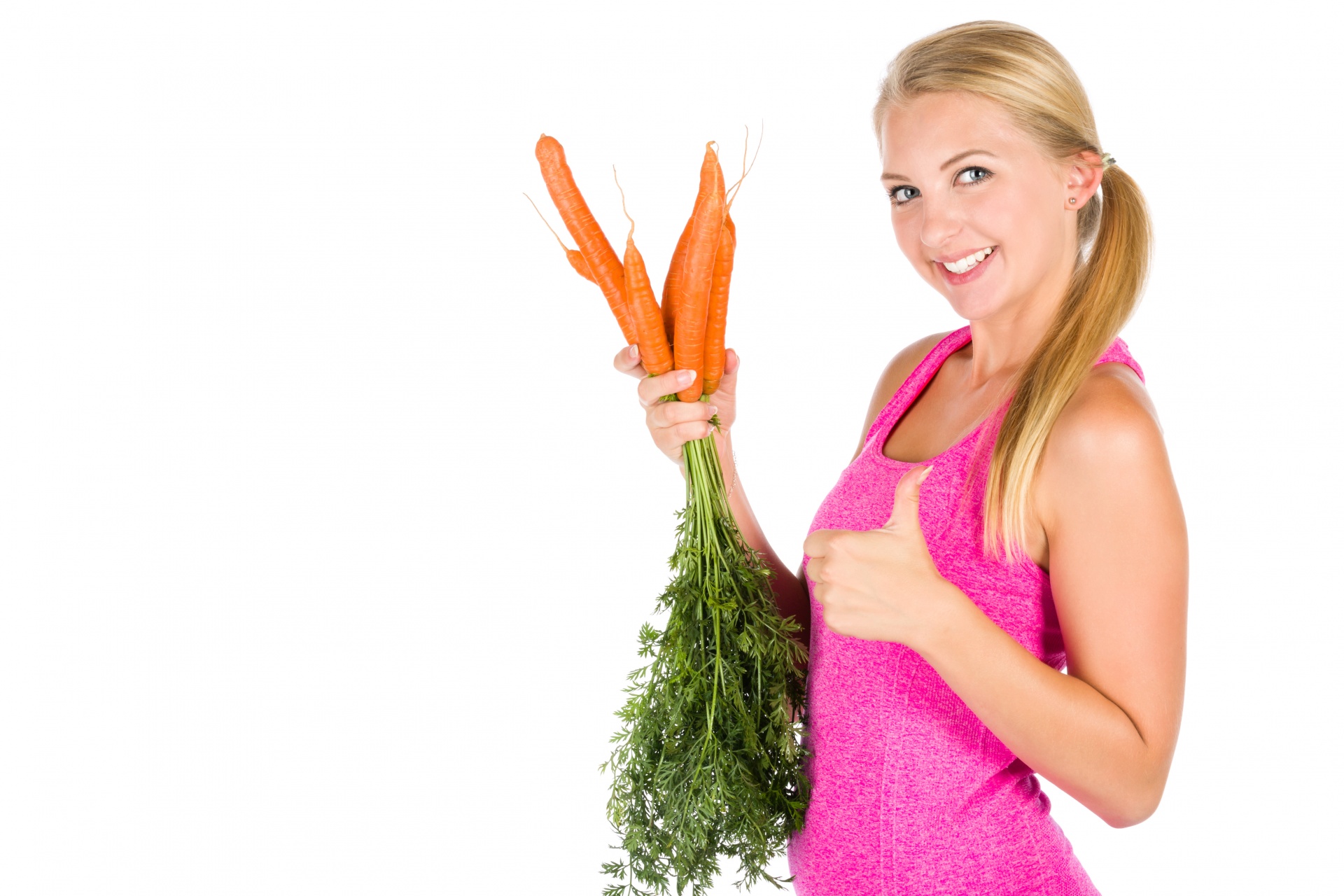 Young healthy woman holding bunch of carrots with her thumb up isolated on white background