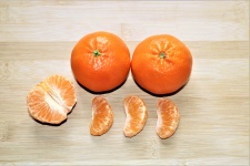 Two Oranges And Segments On Wood