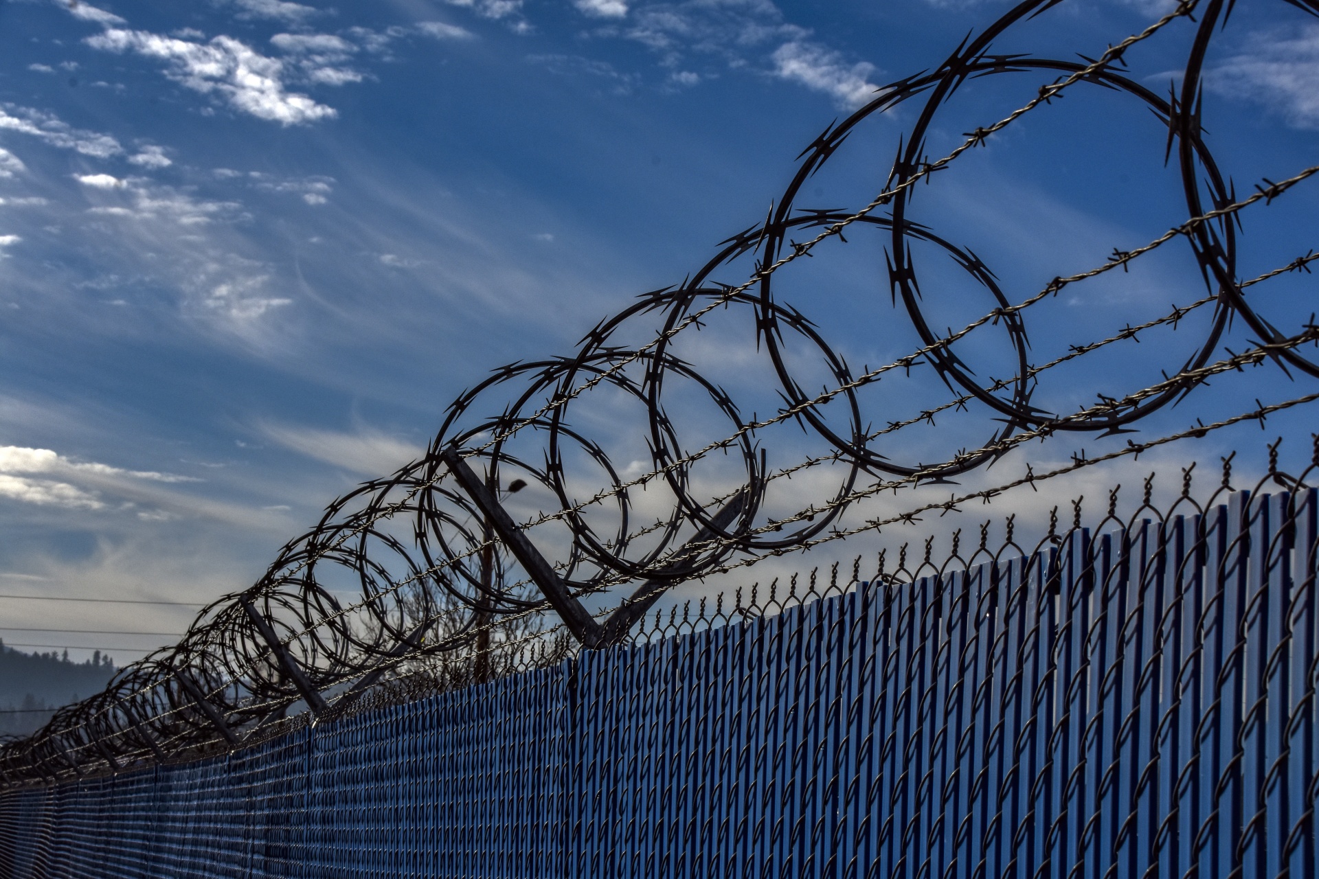 circular barbed wire fence with blue sky and clouds in background