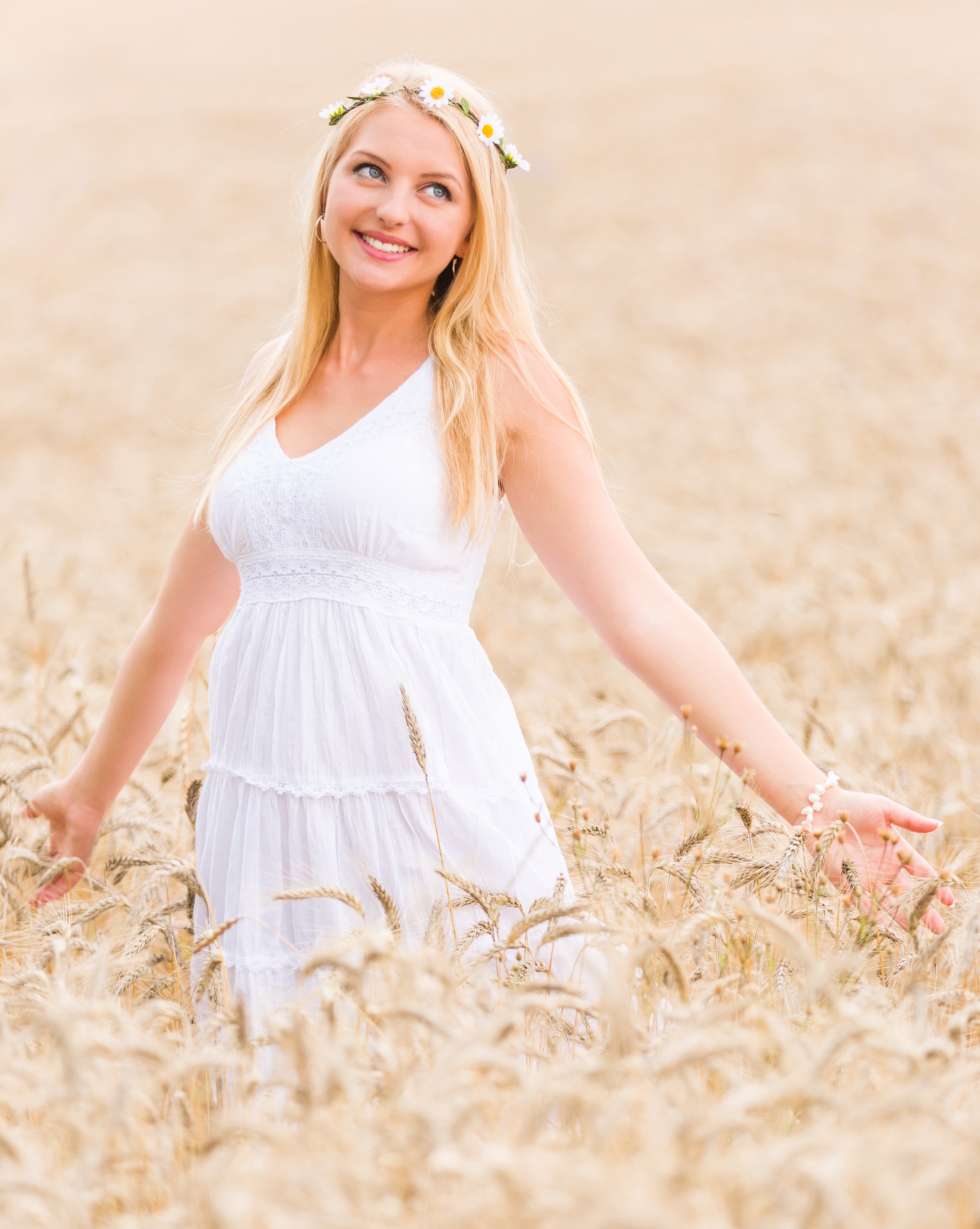 Young blond woman standing in golden wheat field in summer