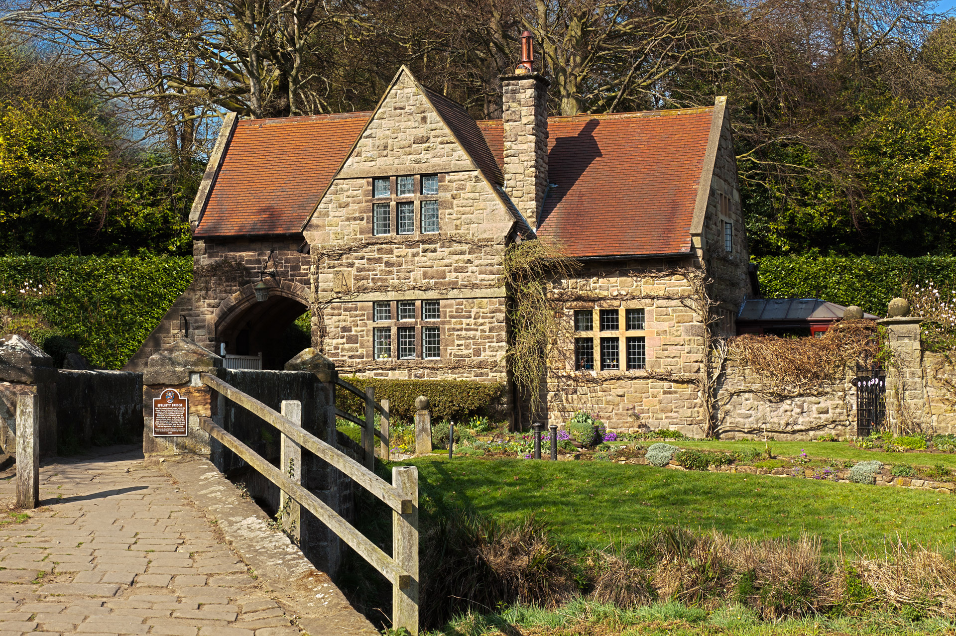 Old english house made from stone with a bridge in in the foreground