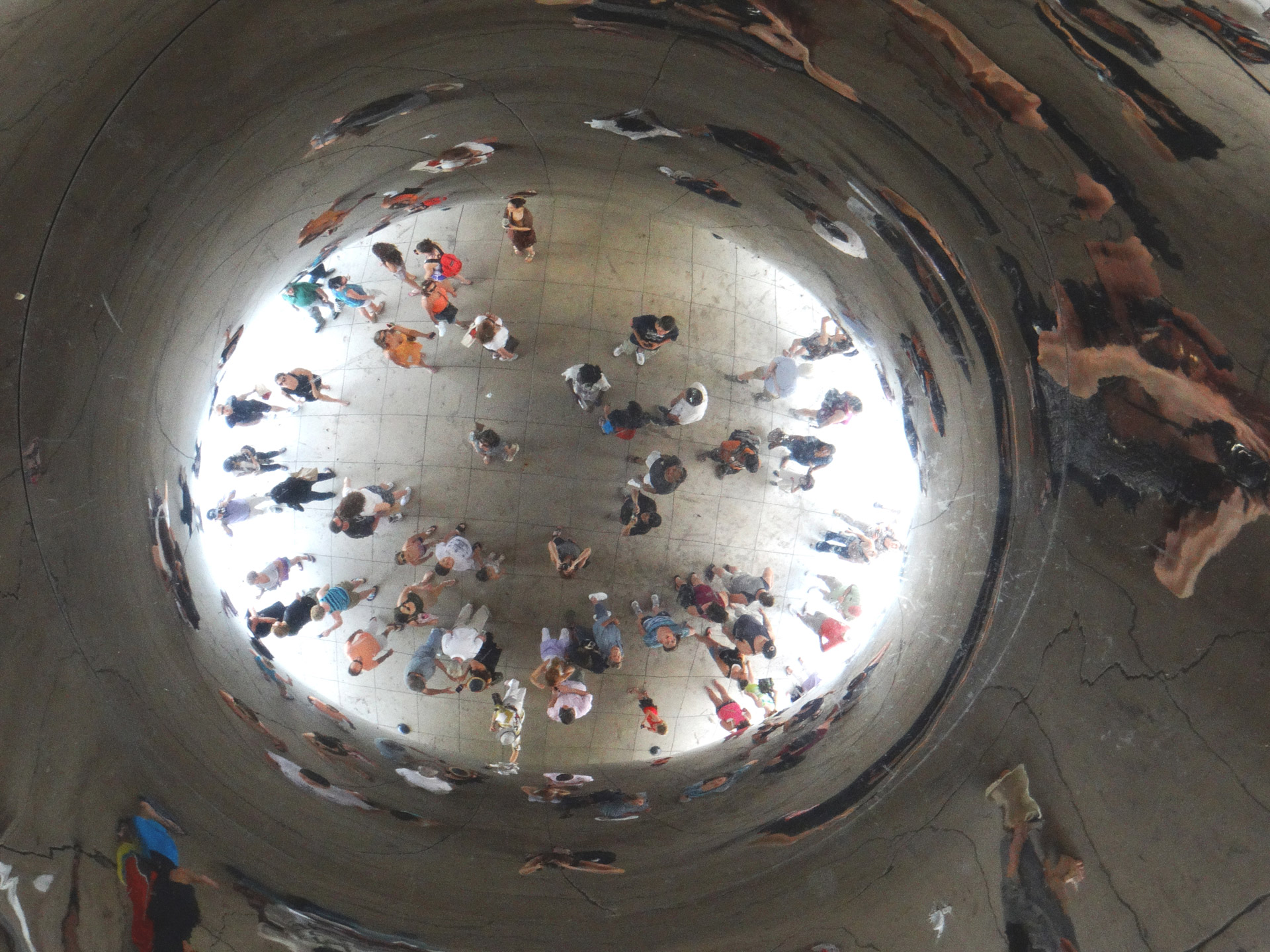 Crowd of people under reflective Bean in Chicago.
