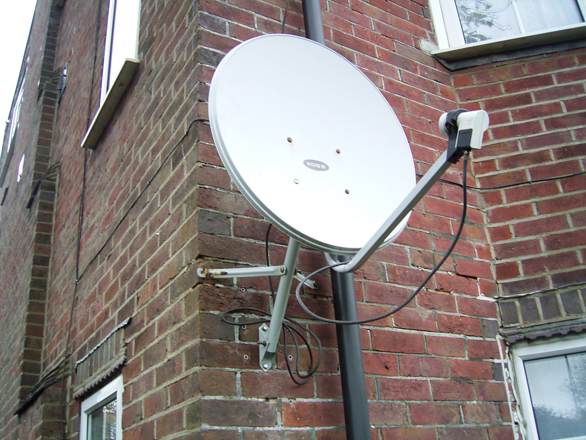 White Satellite Dish On Building Corner
