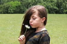 Young Girl Blowing On Dandelion