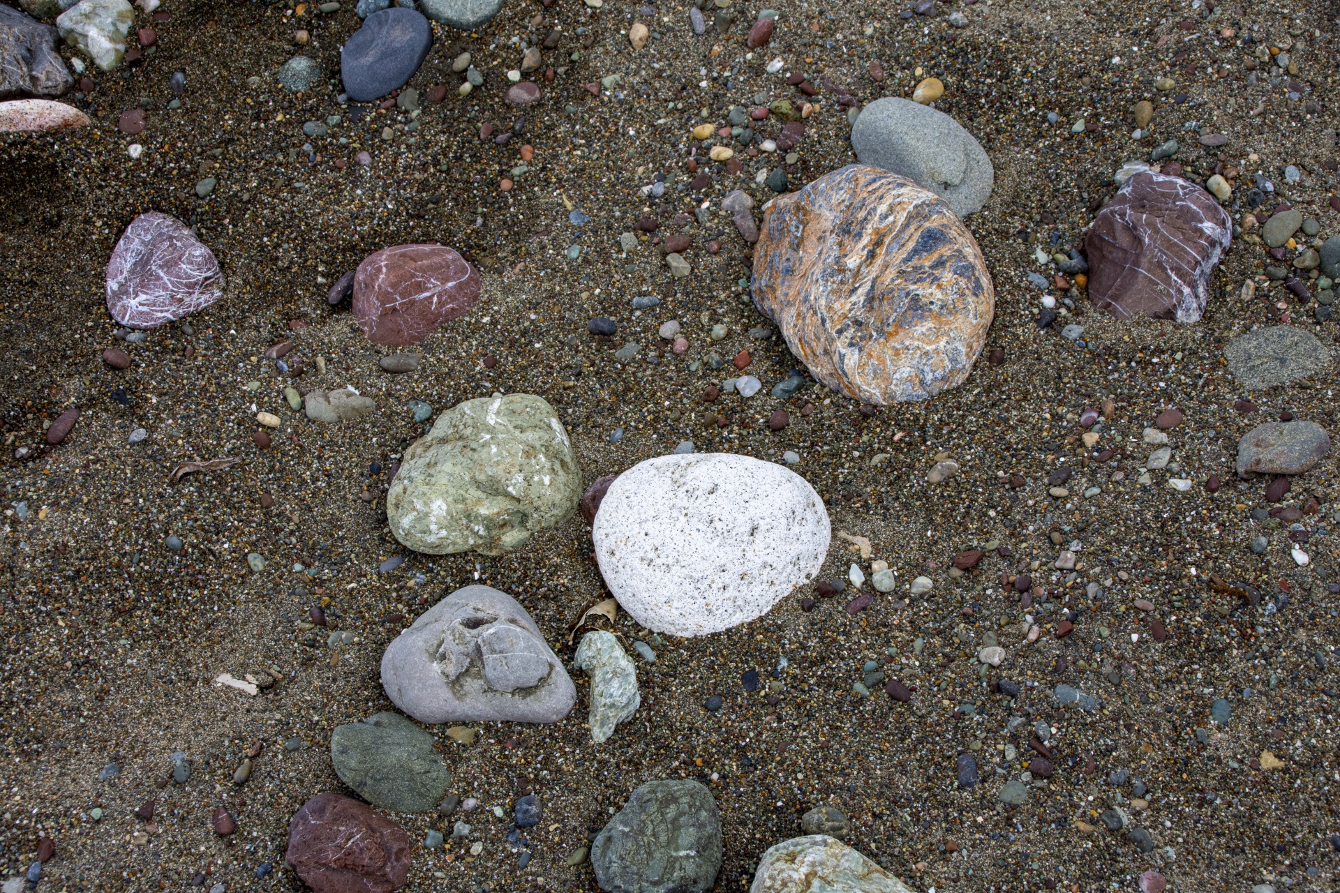 assorted rocks and smooth pebbles on sand at beach