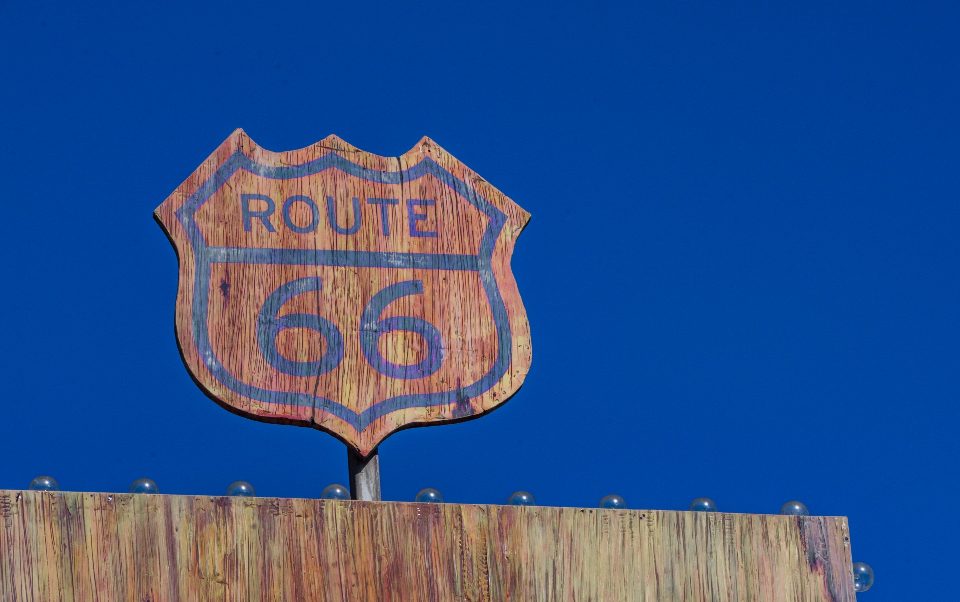 vintage wooden Route 66 road sign with blue text
