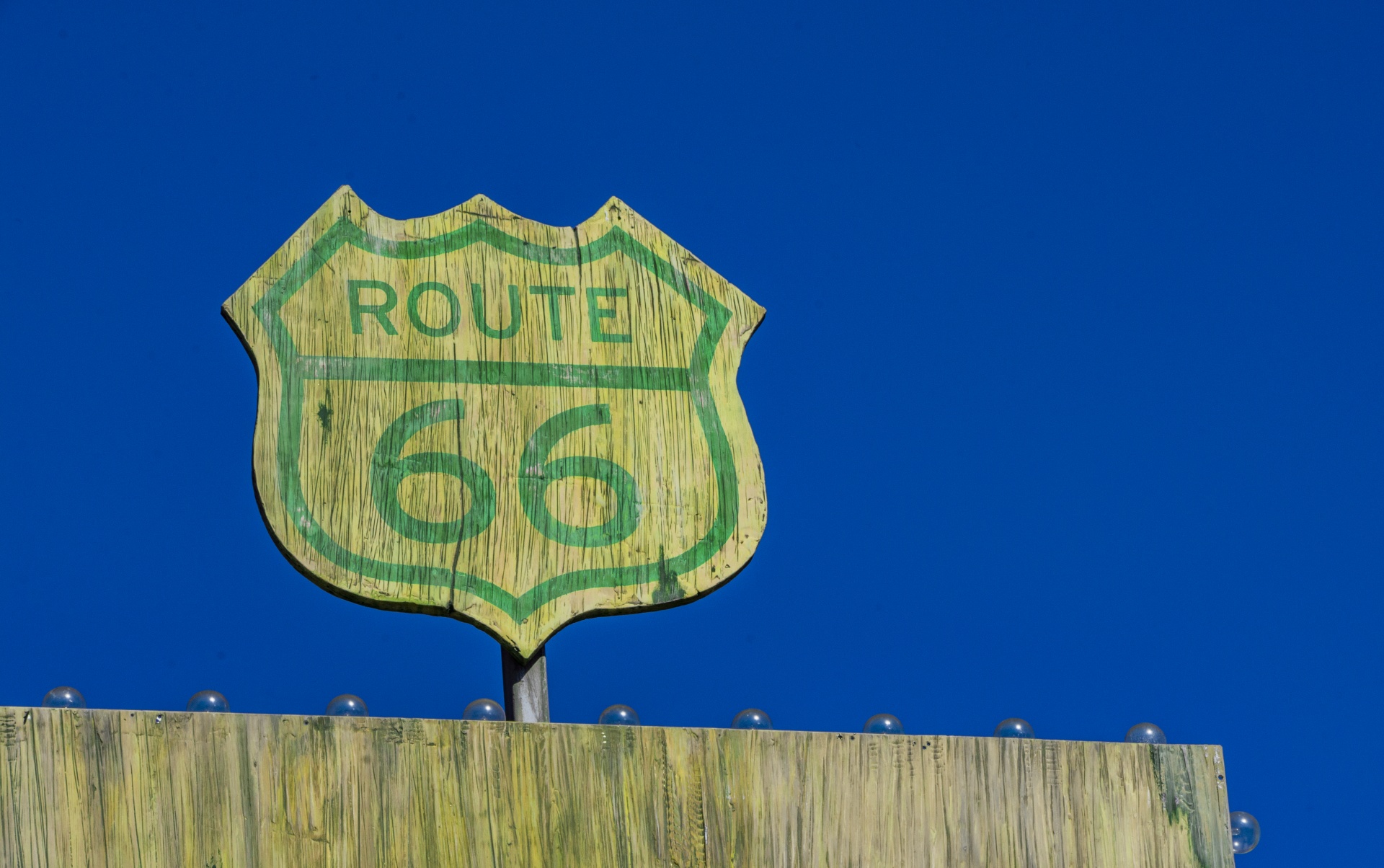 old wooden route 66 sign with green text