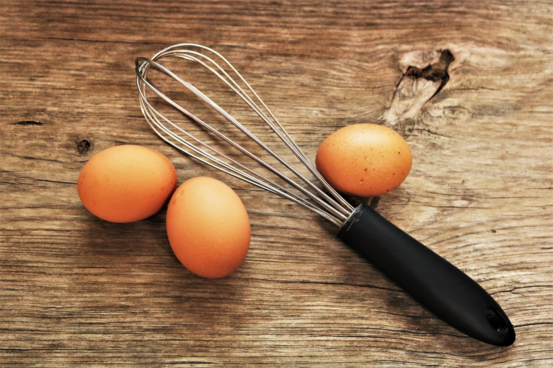 Eggs And Whisk On Wood Table