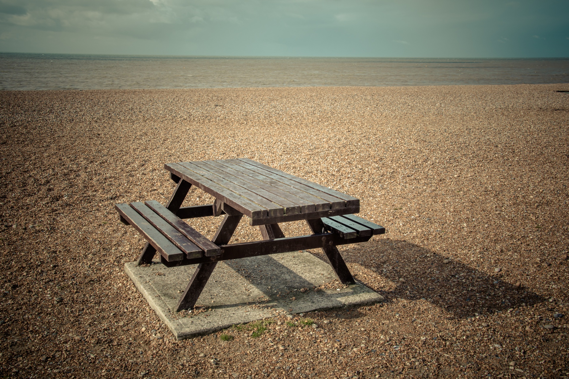 Brown wooden picnic table on a beach