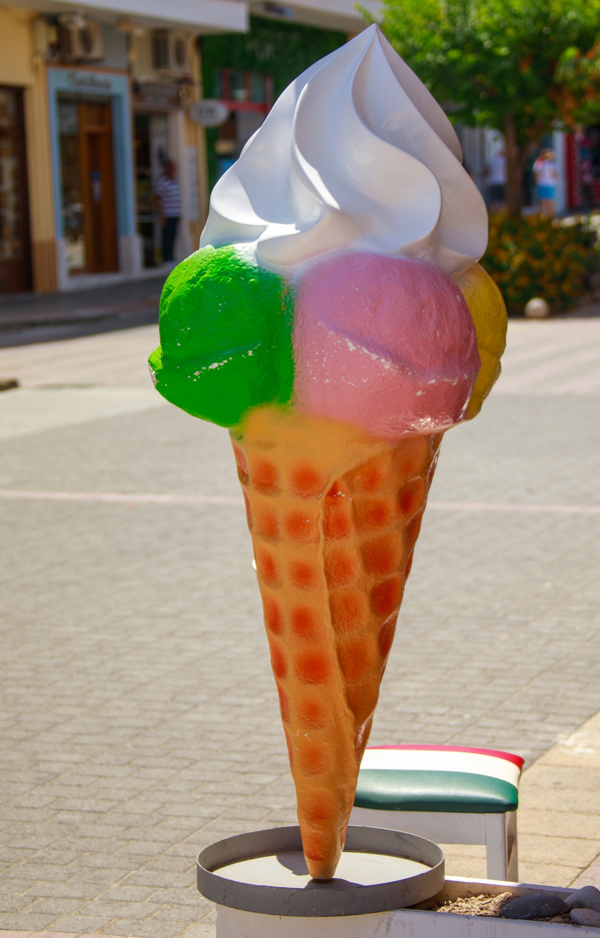 Large colorful plastic ice cream cone sign next to a business which sells ice cream