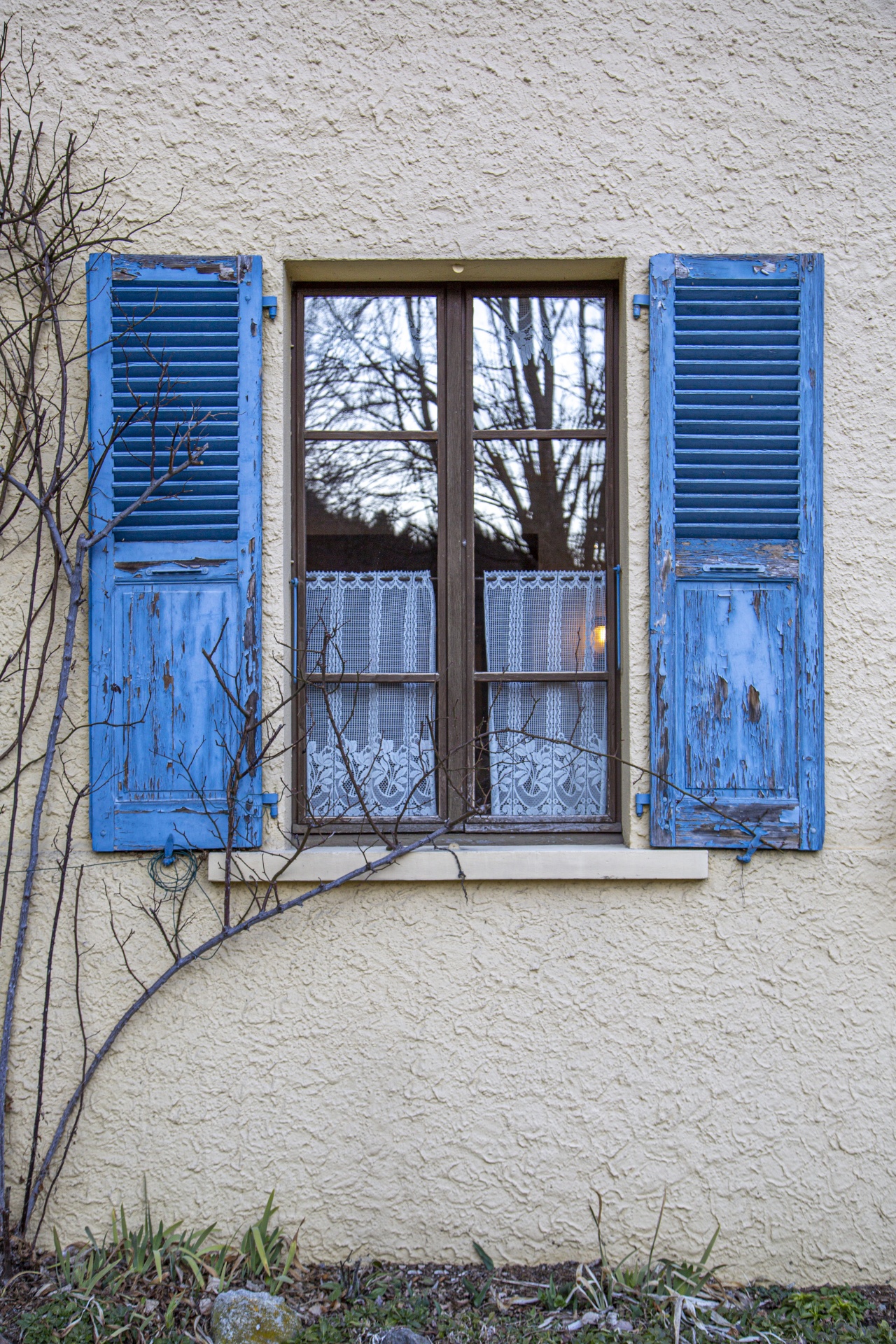 Close-up of a window with Blue wood shutters on a concrete gray wall