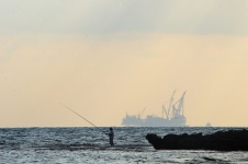Fisherman Against Oilrig Silhouette