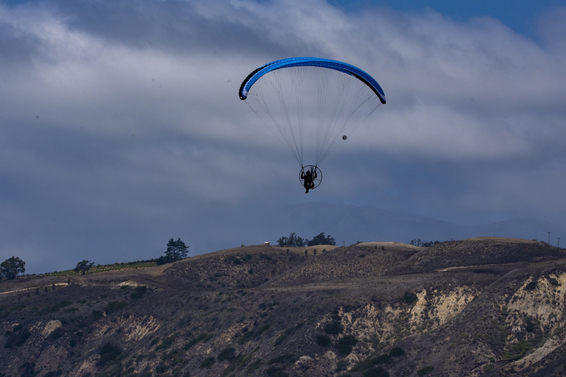 man soaring over mountains in a high performance paramotor