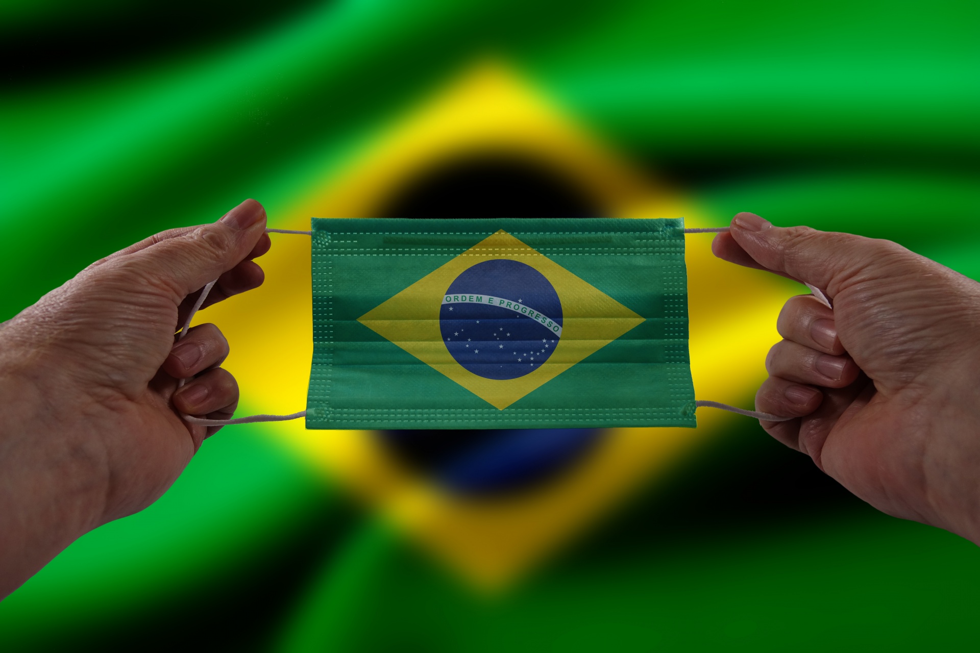 Hands holding face mask with Brazil flag