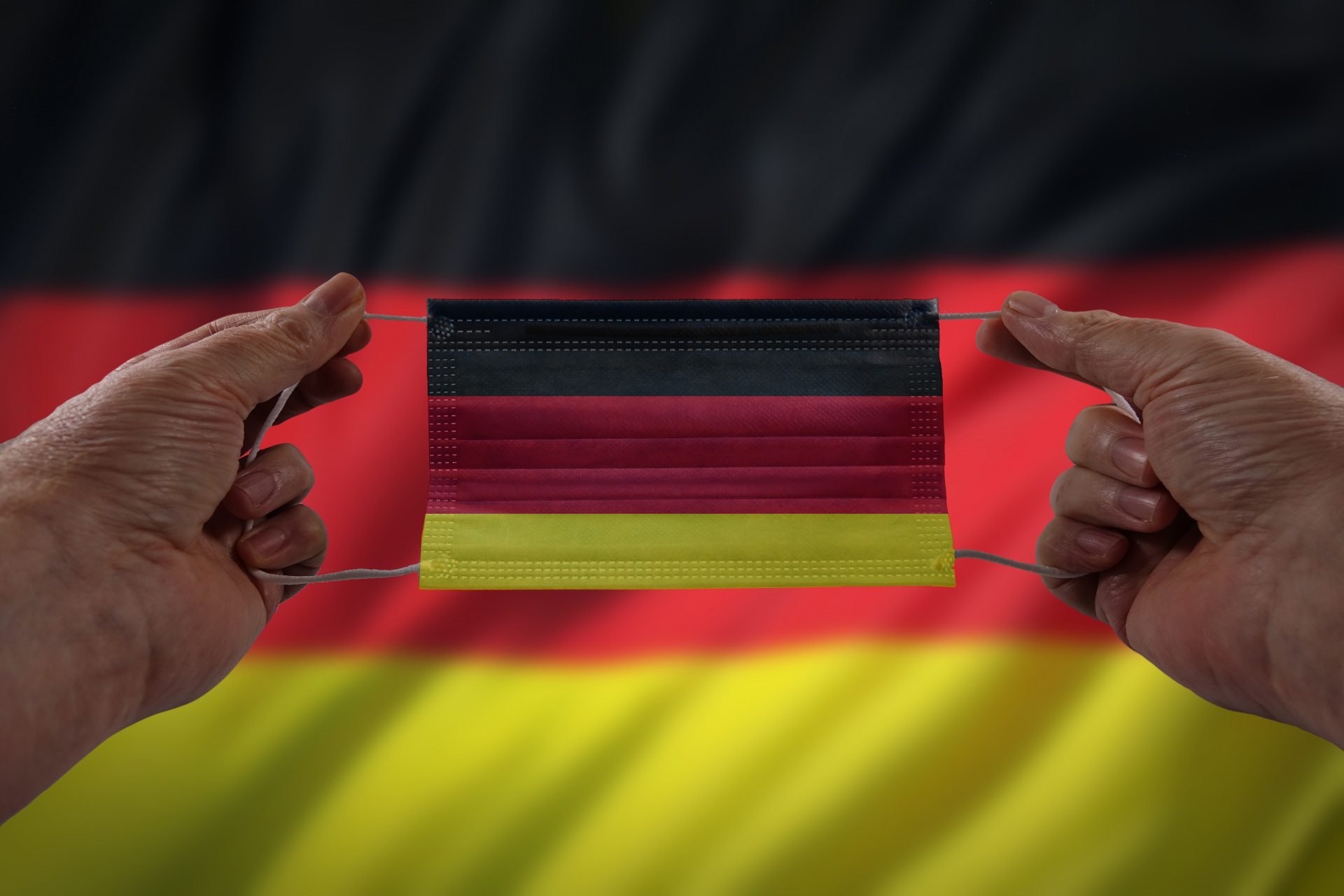 Hands hold face mask with Germany flag