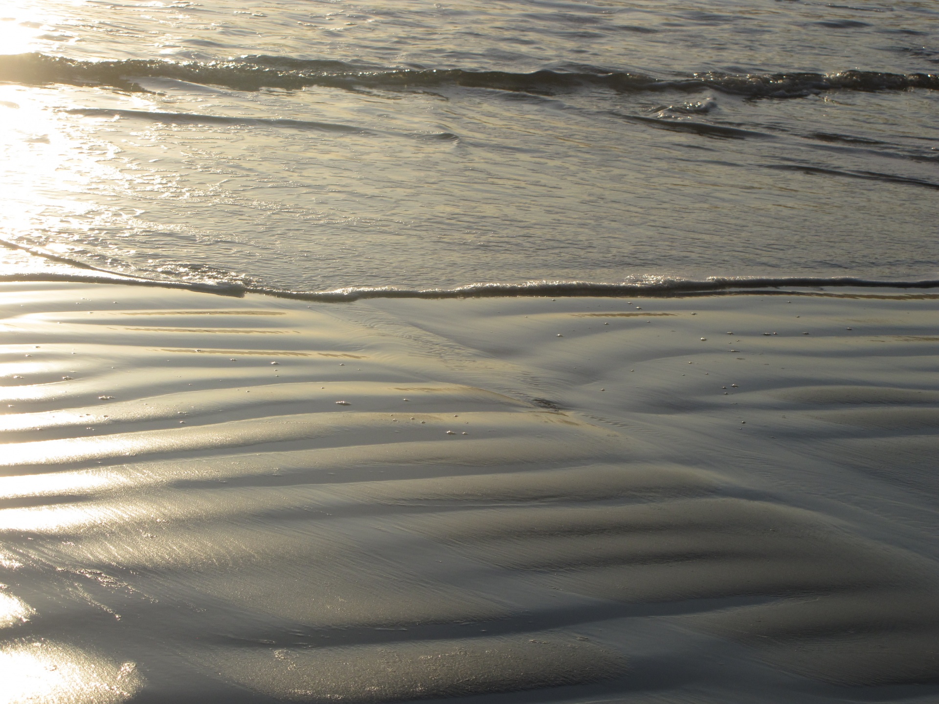 Wet sand and gentle waves on beach