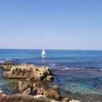 Sailboat Near Rocks On Blue Sea