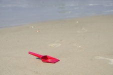 Red Plastic Spade Lying On Beach