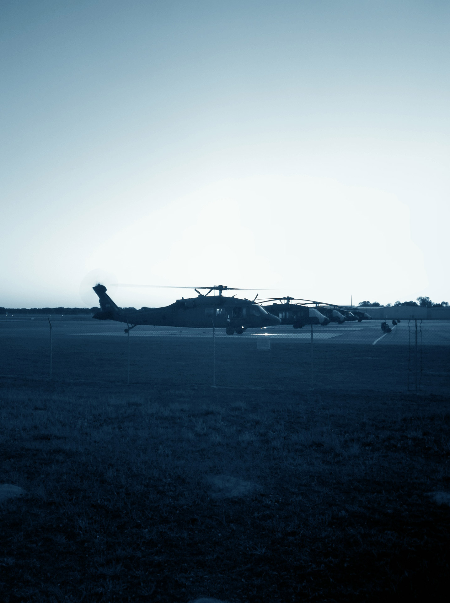 This picture is of Black Hawk Helicopters that are waiting to be refueled during dusk.