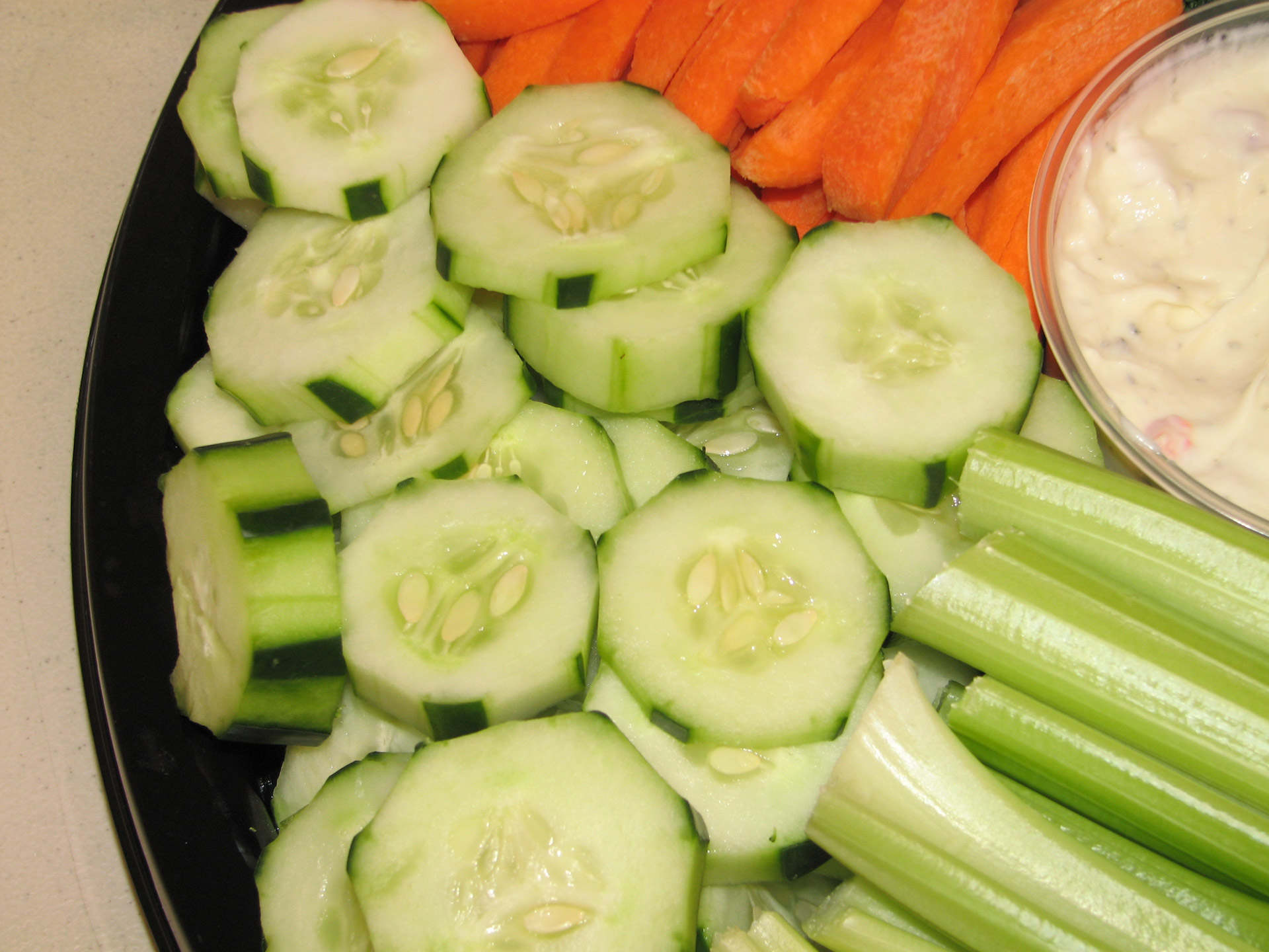 An image of a healthy snack with cucumbers, carrots, celery, and dip.