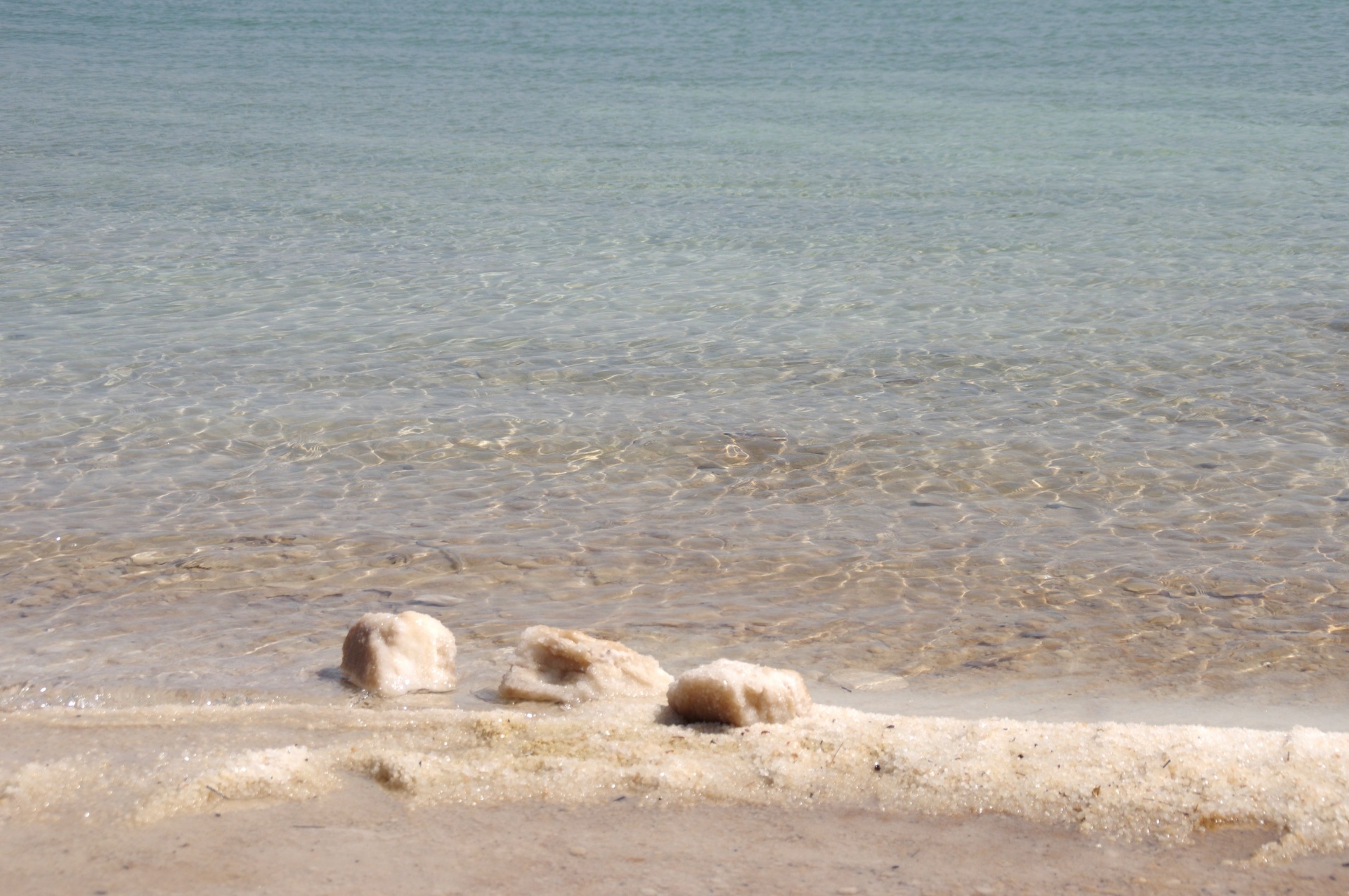 Clumps of large salt rocks at edge of the Dead Sea beach