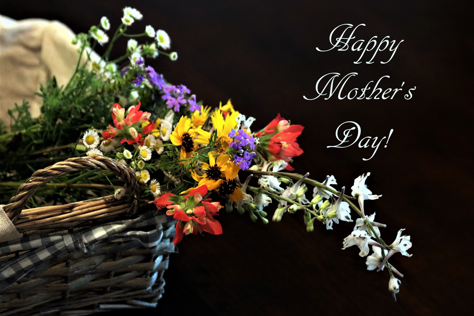 Wildflowers in a basket on a dark background with the text, Happy Mother's Day.