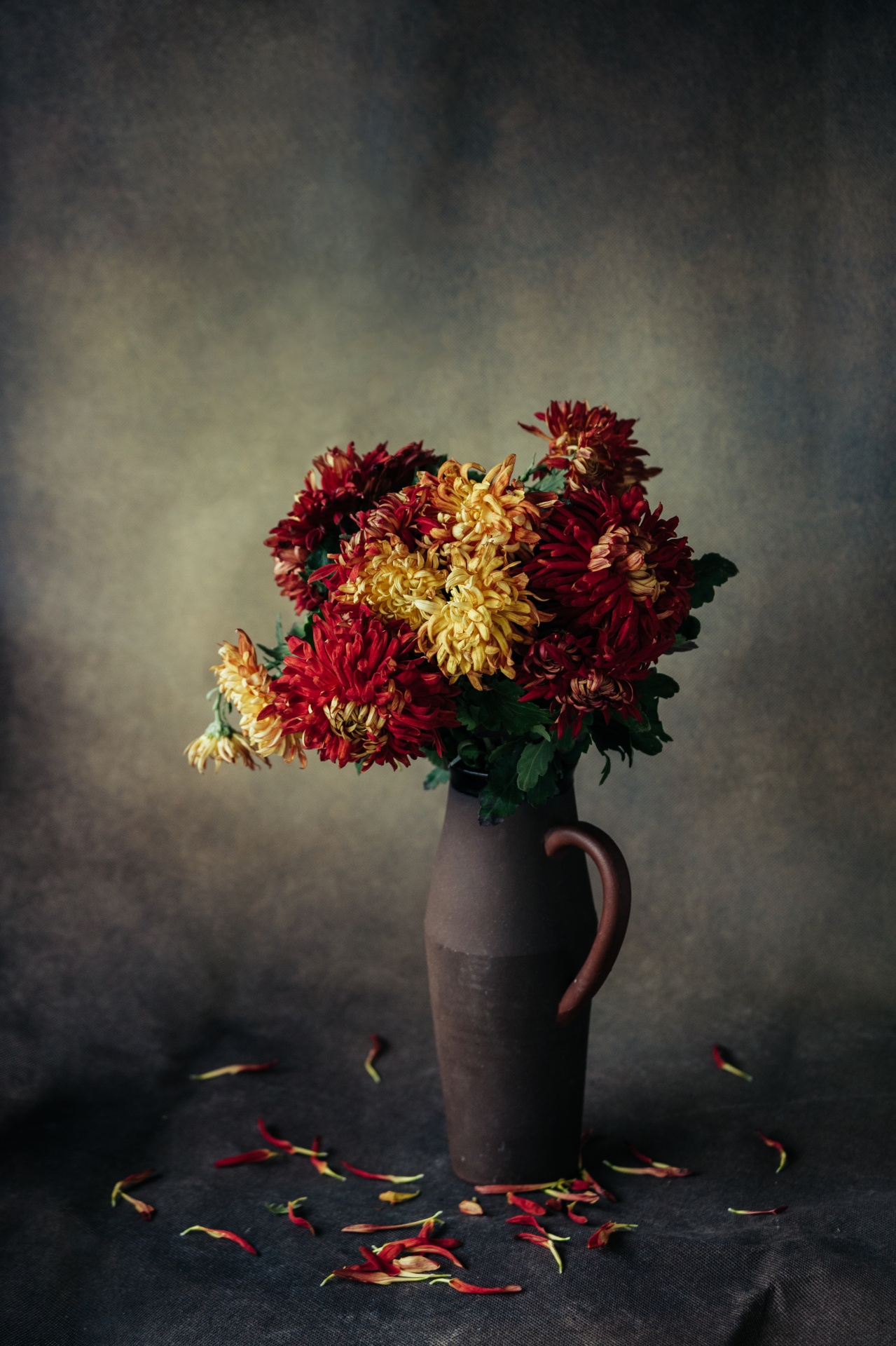 still life decorative red and yellow flowers in old ceramic vase on canvas background natural light