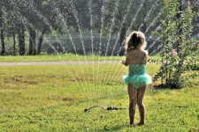 Little Girl Playing In Sprinkler