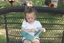 Little Girl Reading A Book Outside
