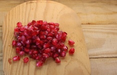 Red Pomegranate Pips On Wood