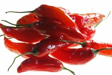 Shiny Red Chilis On A Lit Surface