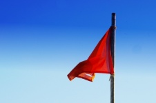 Ripped Red Flag Flying In Wind