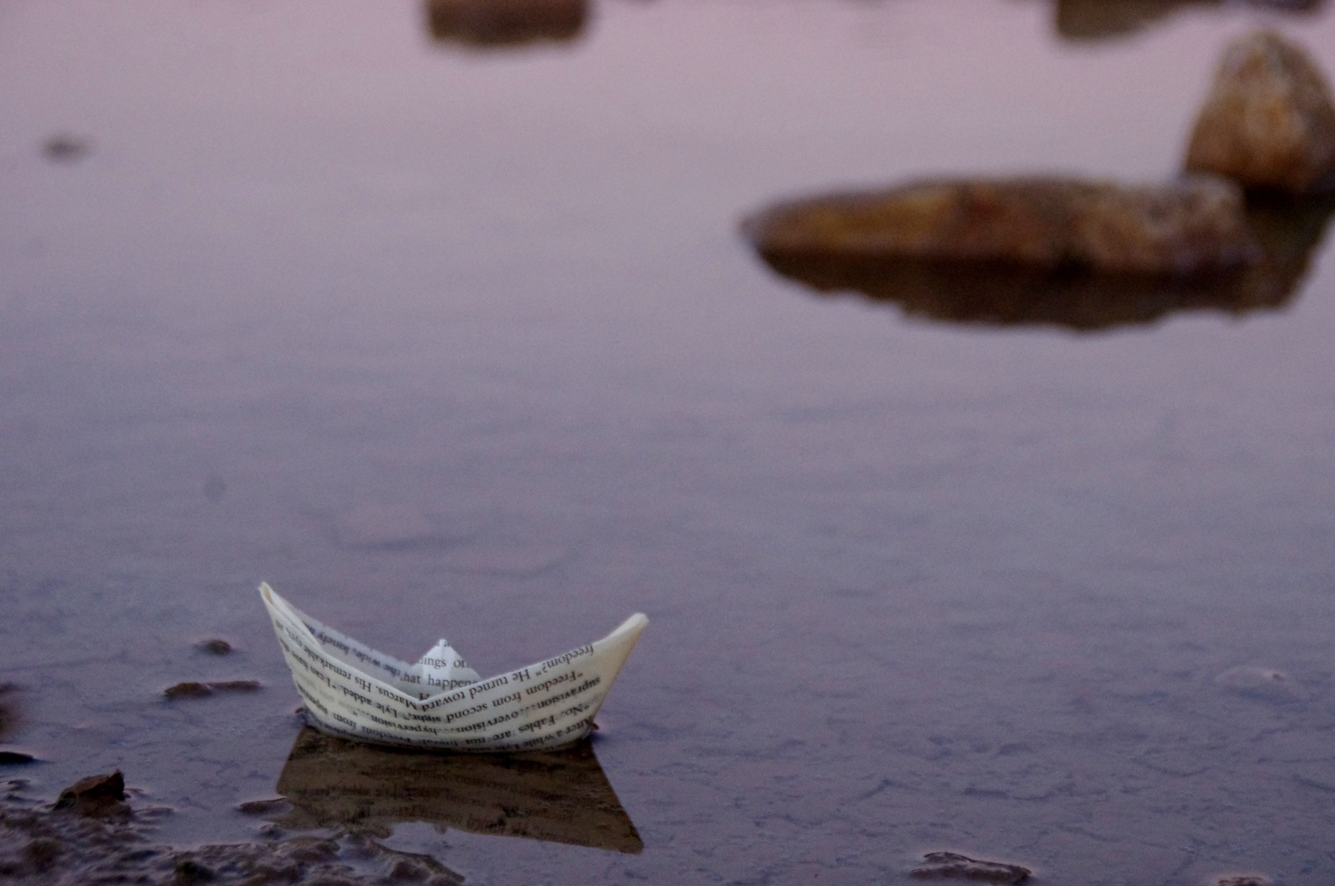 Paper boat on quiet water at sunset