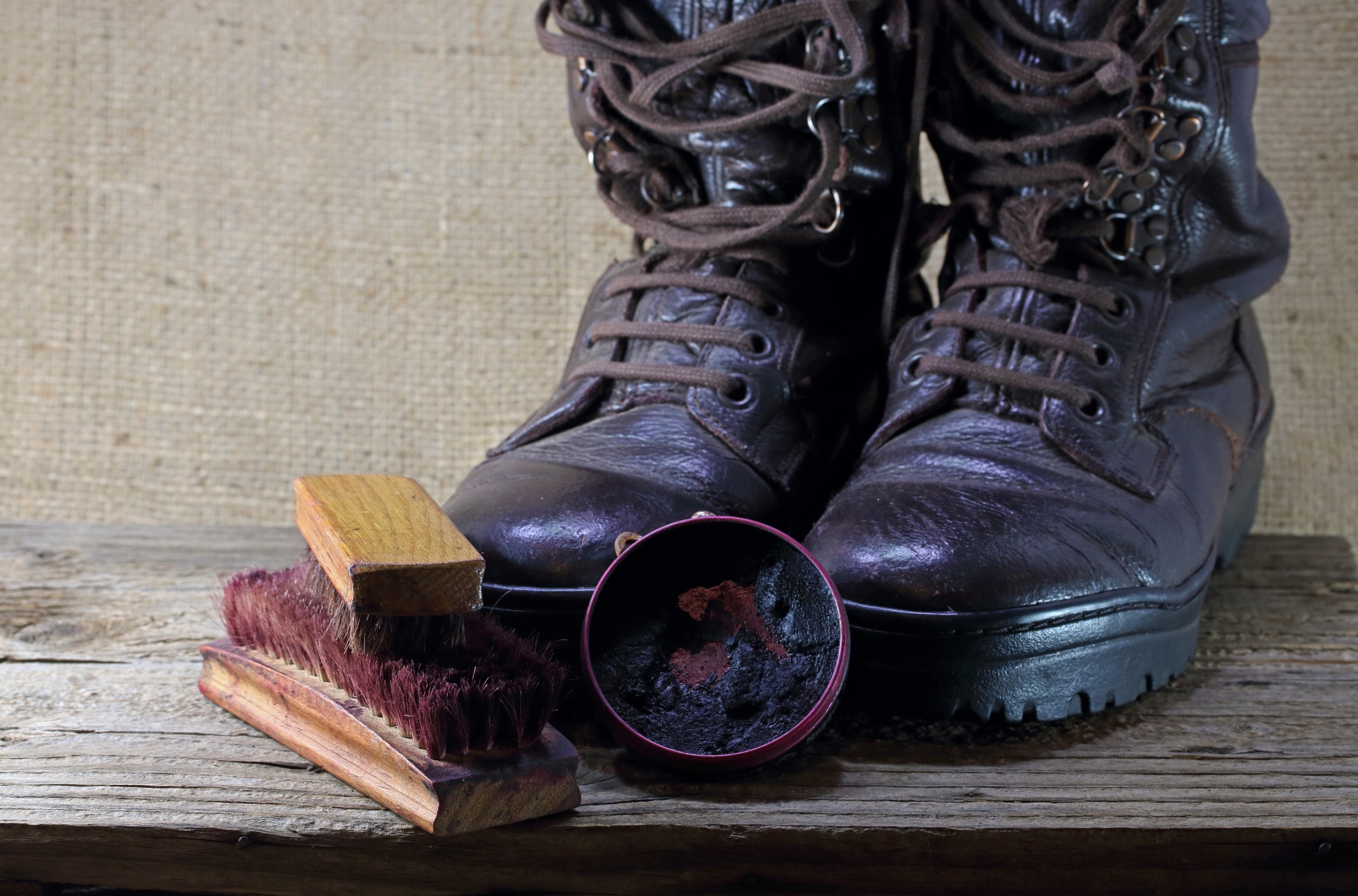 polished combat boots with tin of polish and brushes