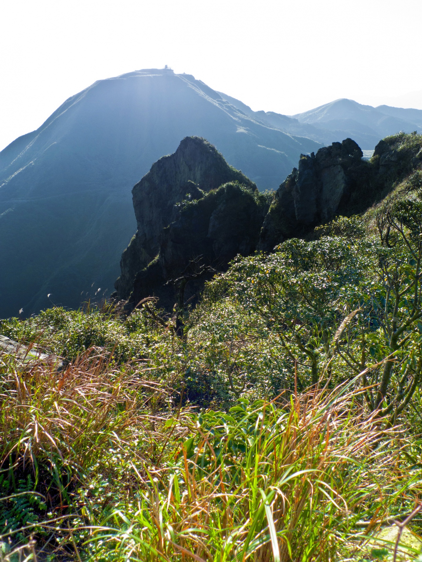 A large slab of volcanic rock, with Tsaoshan Grass Mountain in the background, Banpingshan Trail, Ruifang