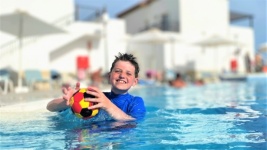 Boy In Holiday Pool With Ball