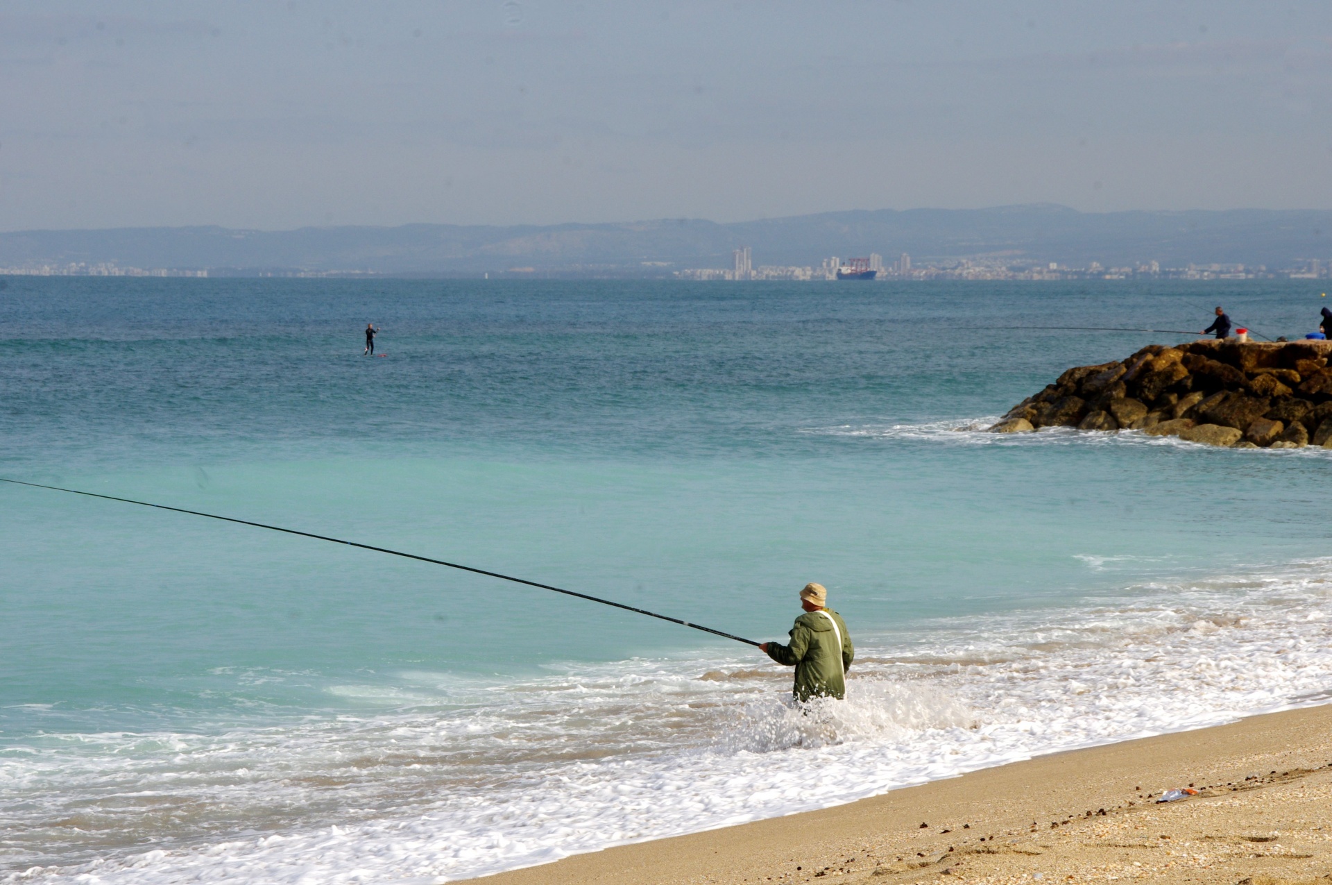 Fisherman in sea with Haifa harbor as background