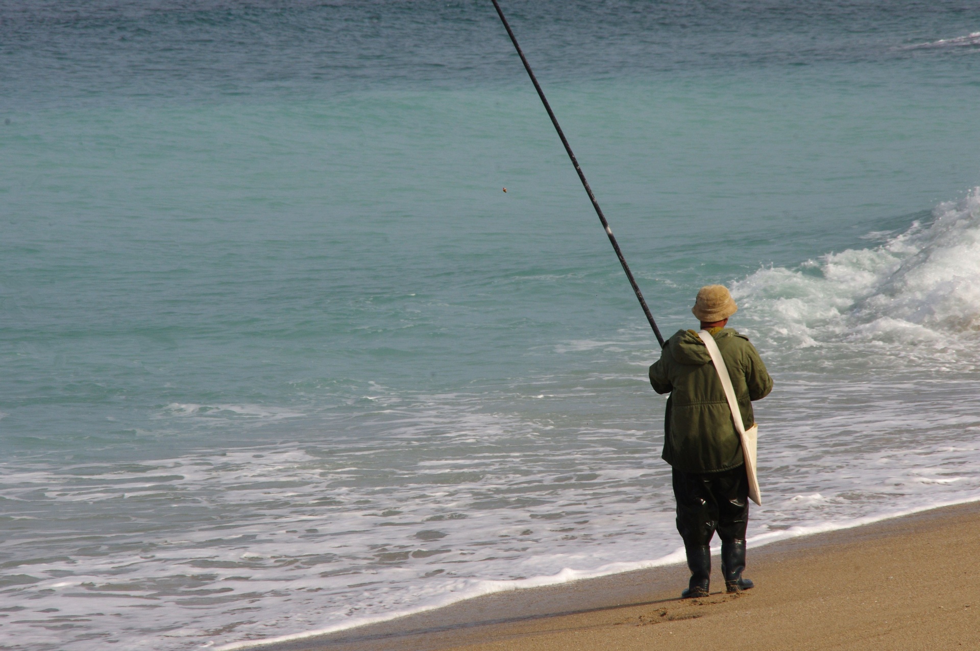 Lonely fisherman standing on sandy beach