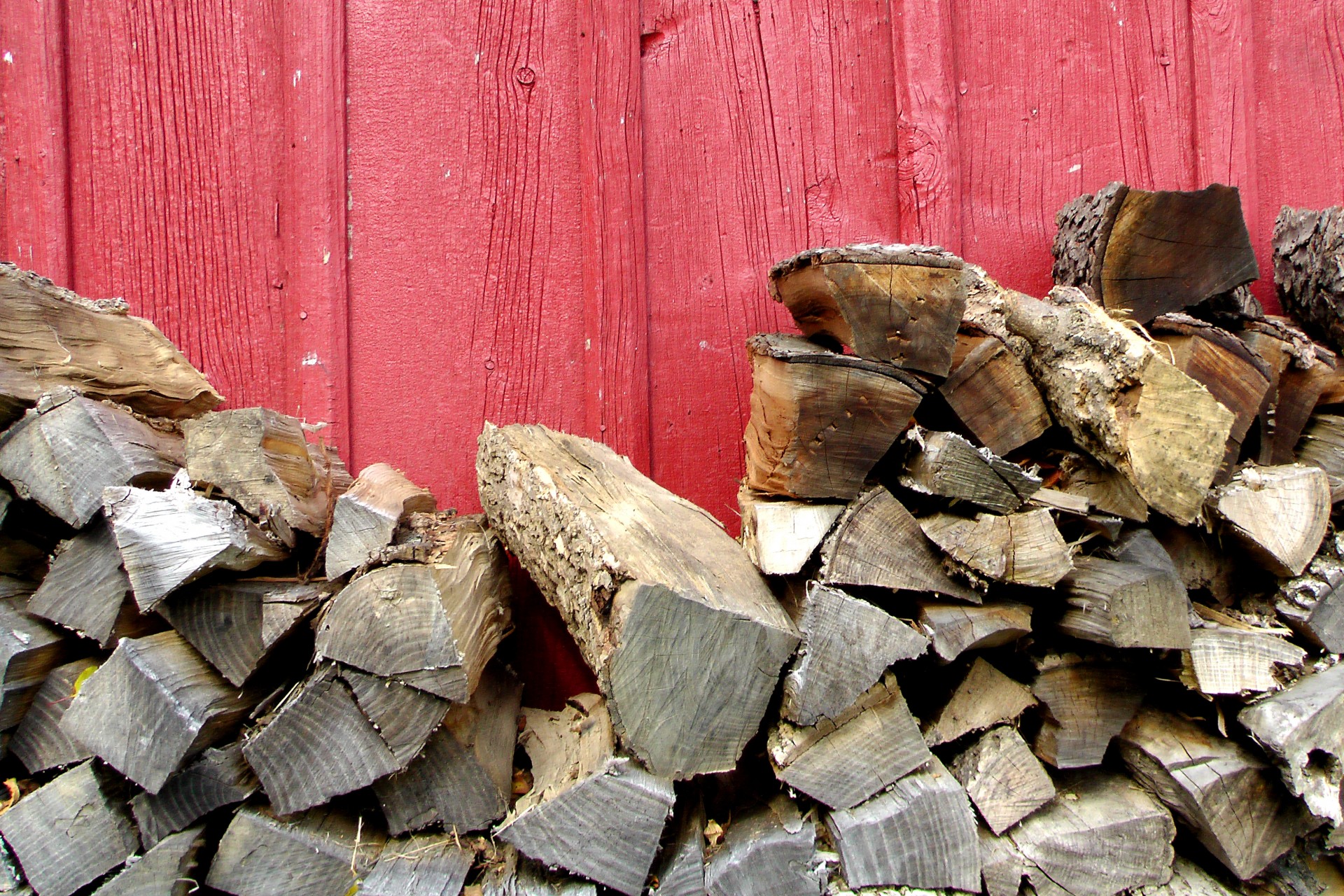 Red painted barn in Amish country with chopped wood piled against it