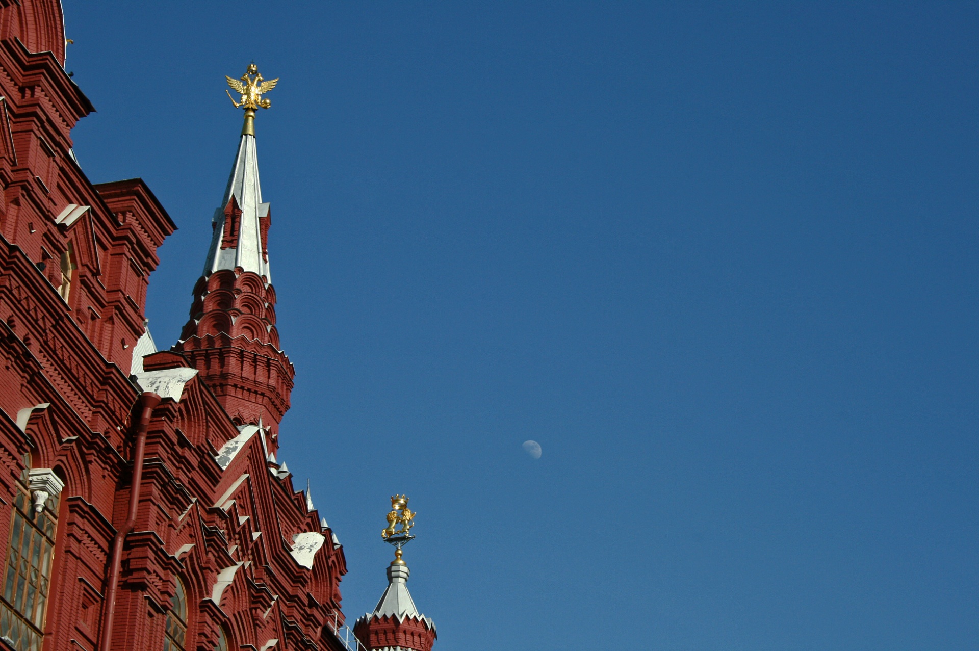 state history museum on red square with partial moon in blue sky in daytime, moscow