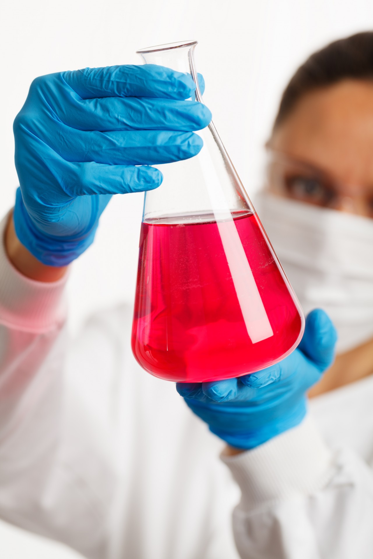 scientist holding an Erlenmeyer flask with pink liquid